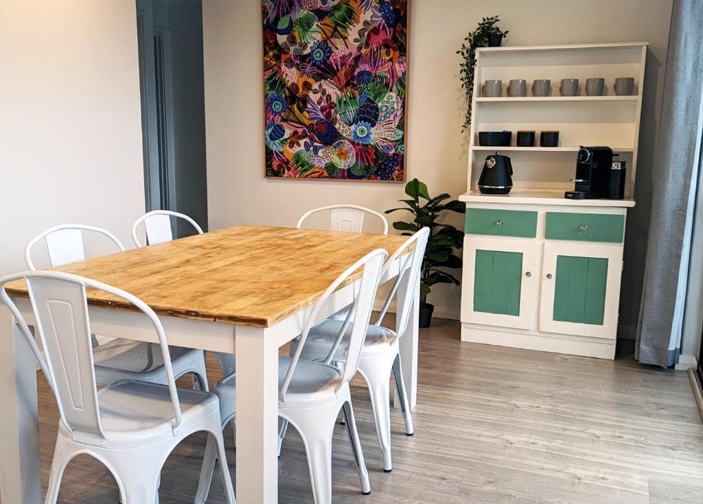 una mesa de comedor con sillas blancas y una pintura en Relaxing Home Close to Nature, en Bunbury