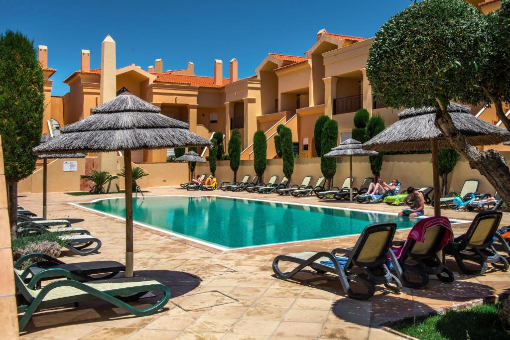 un complejo con una piscina con tumbonas y sombrillas en Baia da Luz Resort en Luz