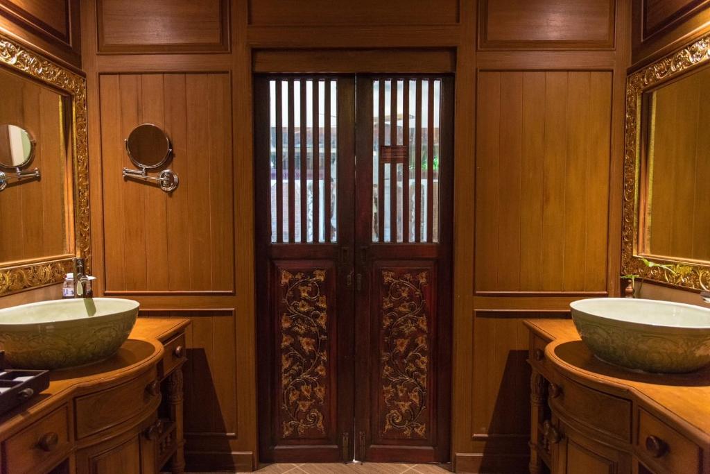 a bathroom with two sinks and two mirrors at Khum Phaya Resort & Spa Boutique Collection in Chiang Mai