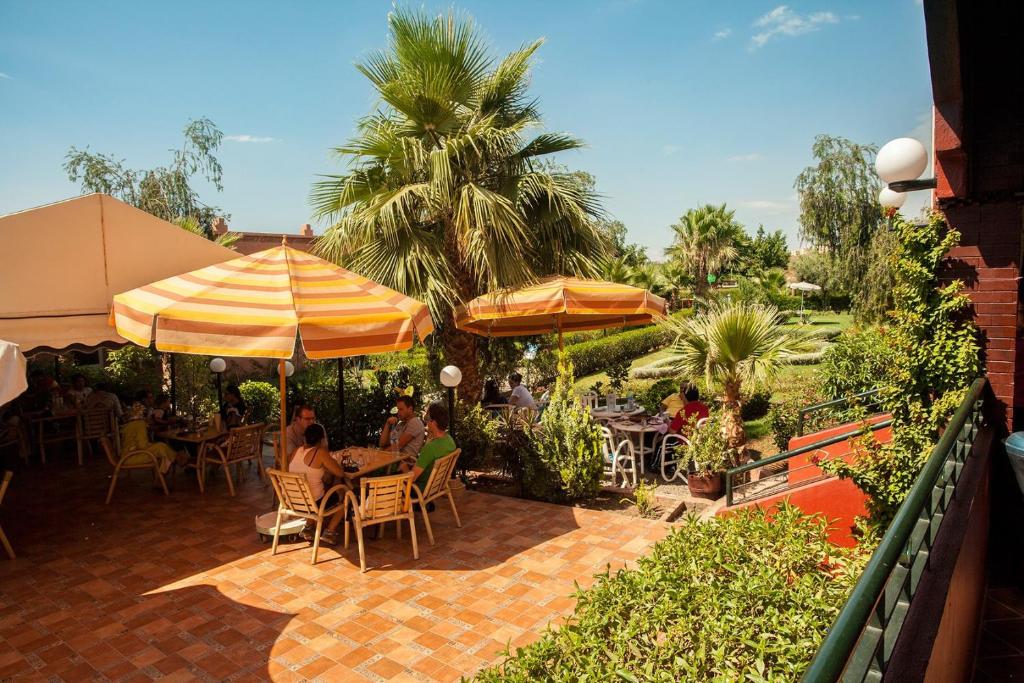 un patio con mesas, sillas y sombrillas en Luxurious apartment - secure and close to Marrakech, en Tahannout