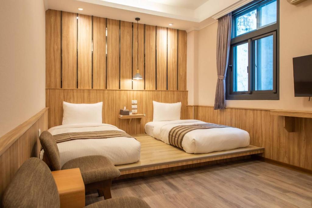 a bedroom with two beds and a desk and a window at Shan Shui Hostel in Hualien City