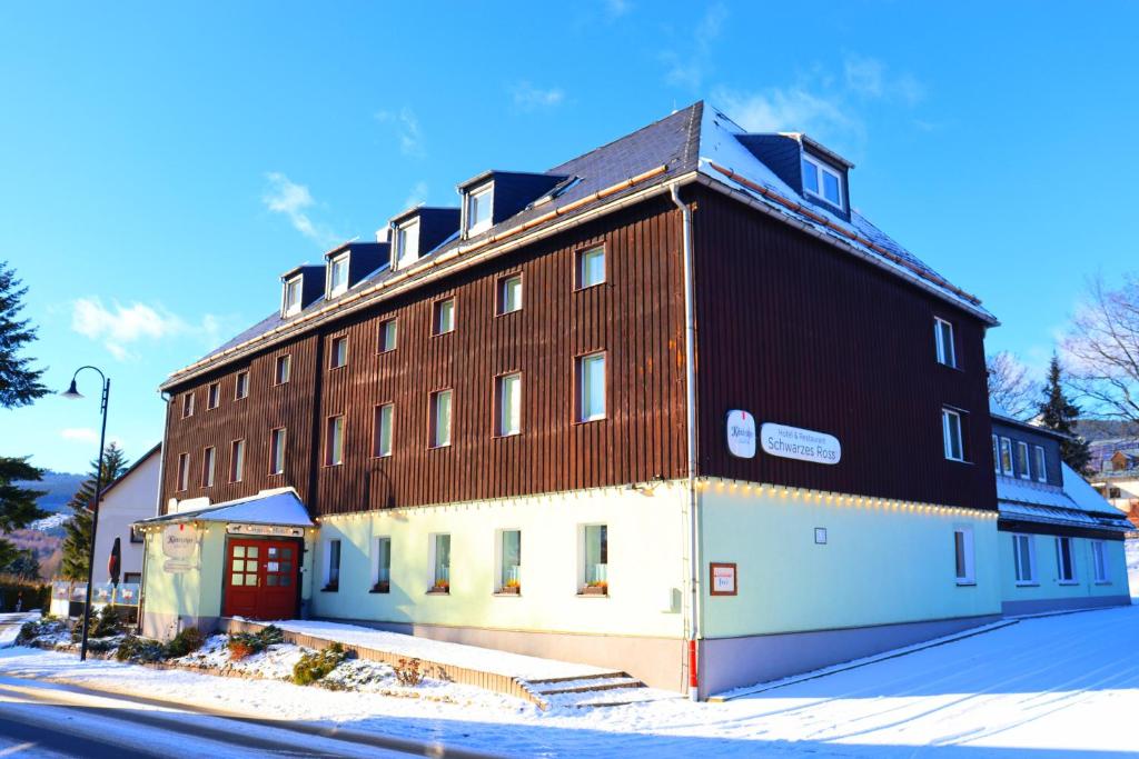a large brown and white building next to a street at Schwarzes Ross Hotel & Restaurant Oberwiesenthal in Kurort Oberwiesenthal