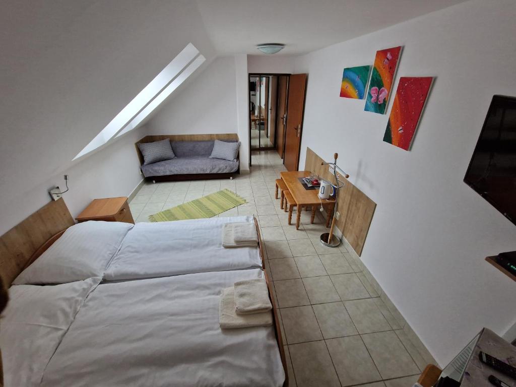 1 dormitorio en el ático con 2 camas y sofá en Penzion Solna Jaskyna, en Turčianske Teplice