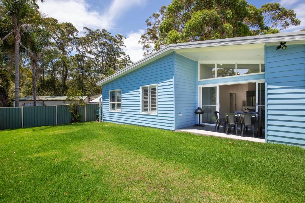 a blue house with a lawn in front of it at Sanctuary Blue Pet Friendly 5 Mins to Hyams Beach in Sanctuary Point
