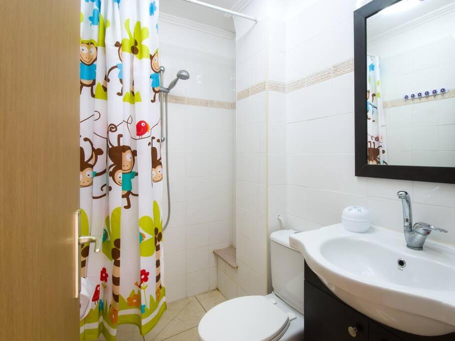 a bathroom with a shower curtain with a toilet and a sink at Alona's Apartments - Beach Apartment in Haifa