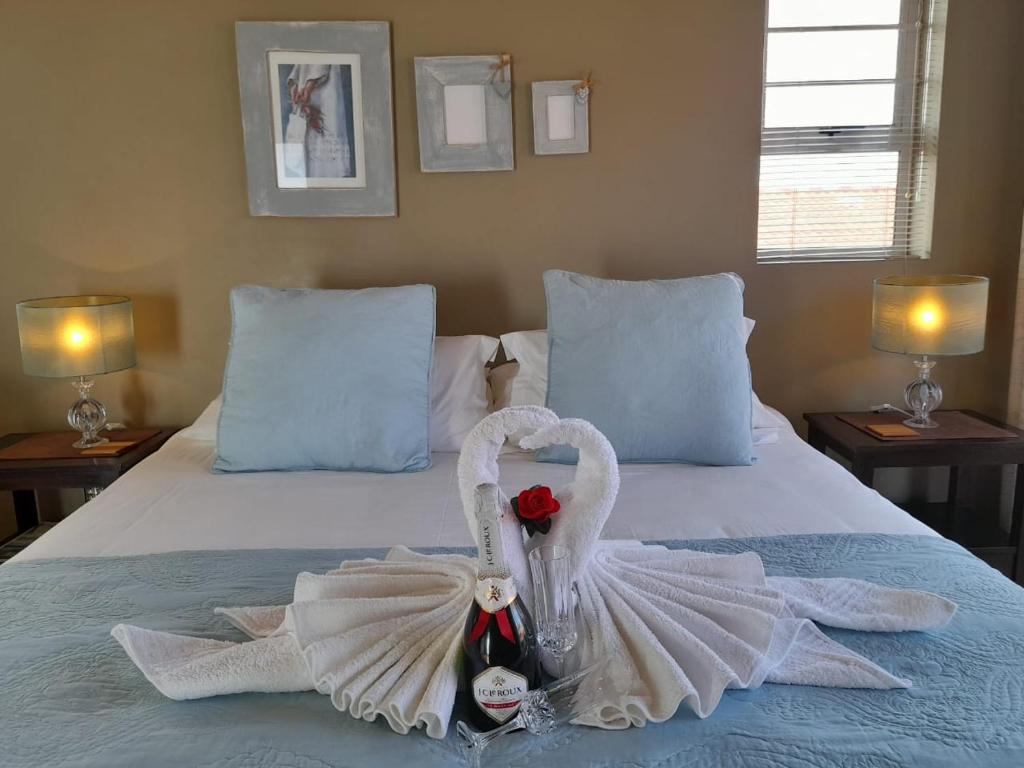 Un par de cisnes están sentados en una cama. en Waves Guest House en Jeffreys Bay