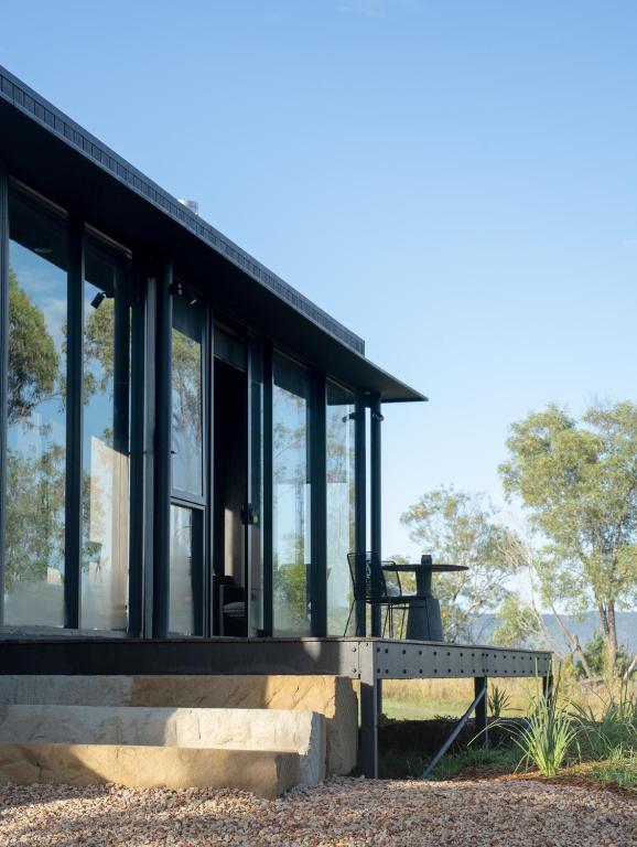 a house with large glass windows and a bench at Wander in the Scenic Rim in Wyaralong