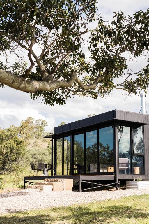 a glass house with a black roof at Wander in the Scenic Rim in Wyaralong