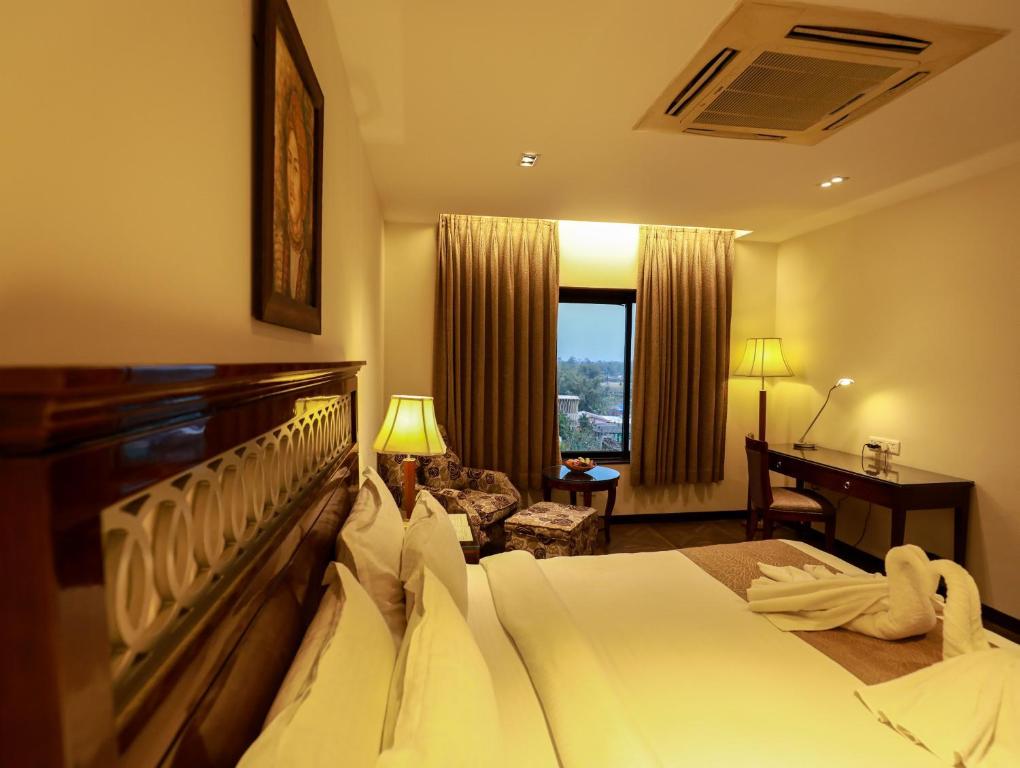 a hotel room with a large bed and a desk at The Greenwood - Tezpur in Tezpur