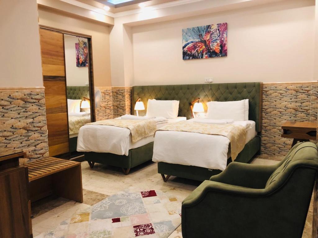 une chambre d'hôtel avec deux lits et un canapé dans l'établissement Royal Eagle Hotel, à An Najaf