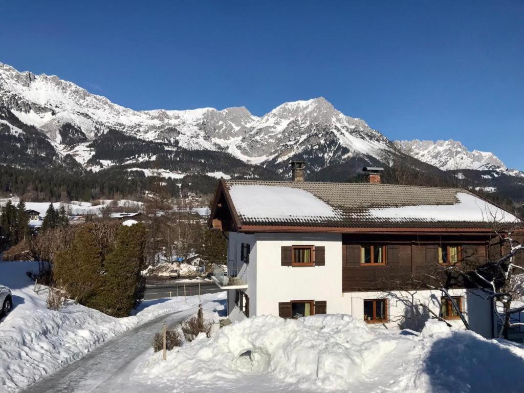 une maison dans la neige avec des montagnes en arrière-plan dans l'établissement D&D Apartment, à Scheffau am Wilden Kaiser