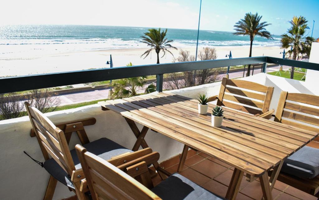 a wooden table and chairs on a balcony with the beach at Apartamento Barrosaplaya1 in Chiclana de la Frontera