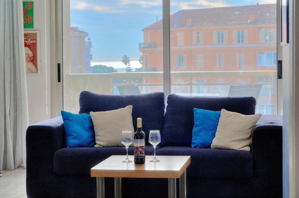 a blue couch with two wine glasses and a table at Very pleasant 2 rooms garage near the beaches in Cannes