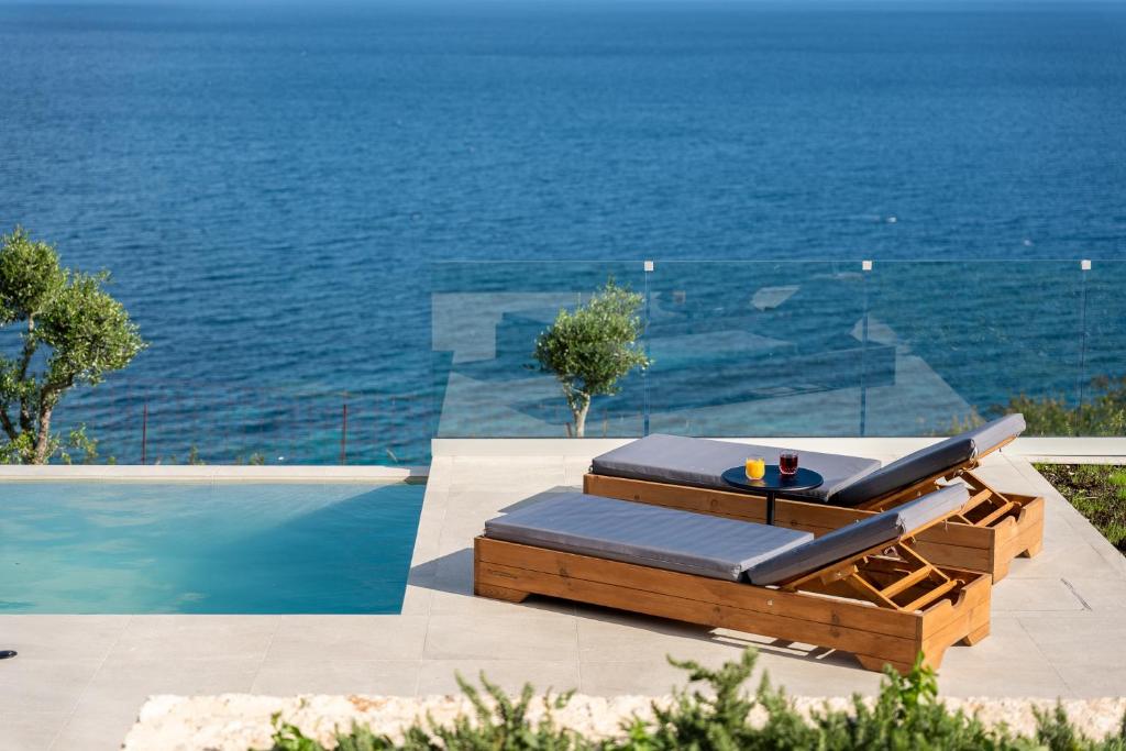 a couple of lounge chairs sitting next to a swimming pool at Ktima Agrapidos - Grandpa Villa in Póros Kefalonias