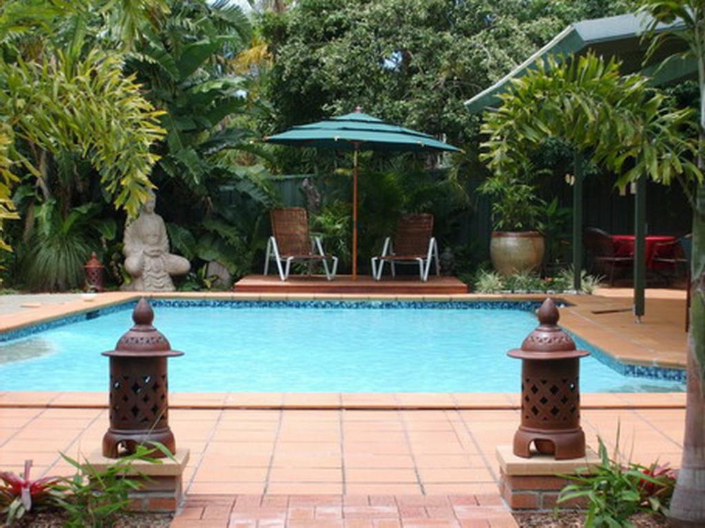 una piscina con sombrilla y sillas en Tantarra Bed & Breakfast en Warners Bay