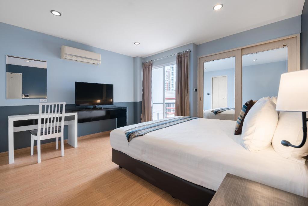a bedroom with a bed and a desk and a television at iCheck inn Residences Sathorn in Bangkok