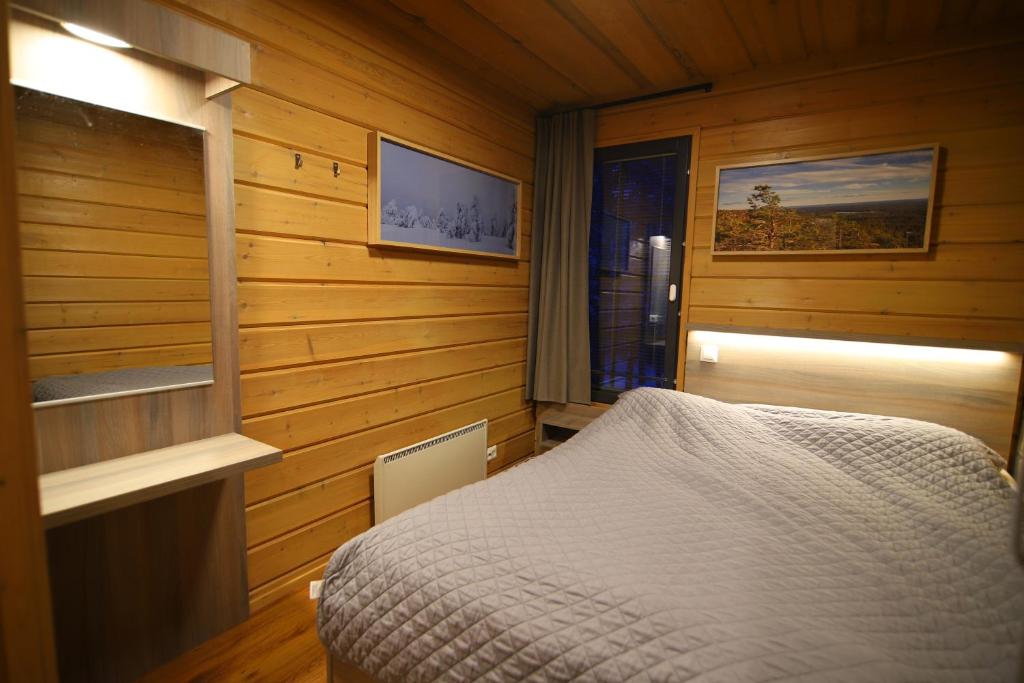 sypialnia z łóżkiem w pokoju z drewnianymi ścianami w obiekcie Tunturipöllö 2 w mieście Ruka