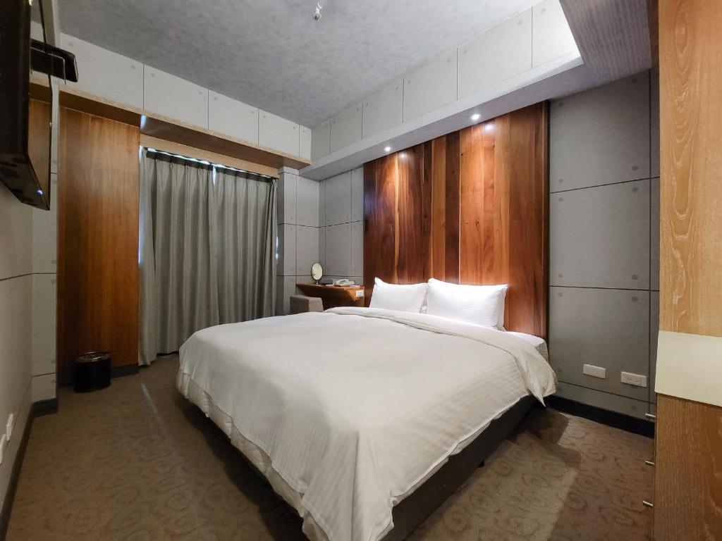 a bedroom with a large white bed with a wooden headboard at CHECK inn Express Taichung Fengchia in Taichung
