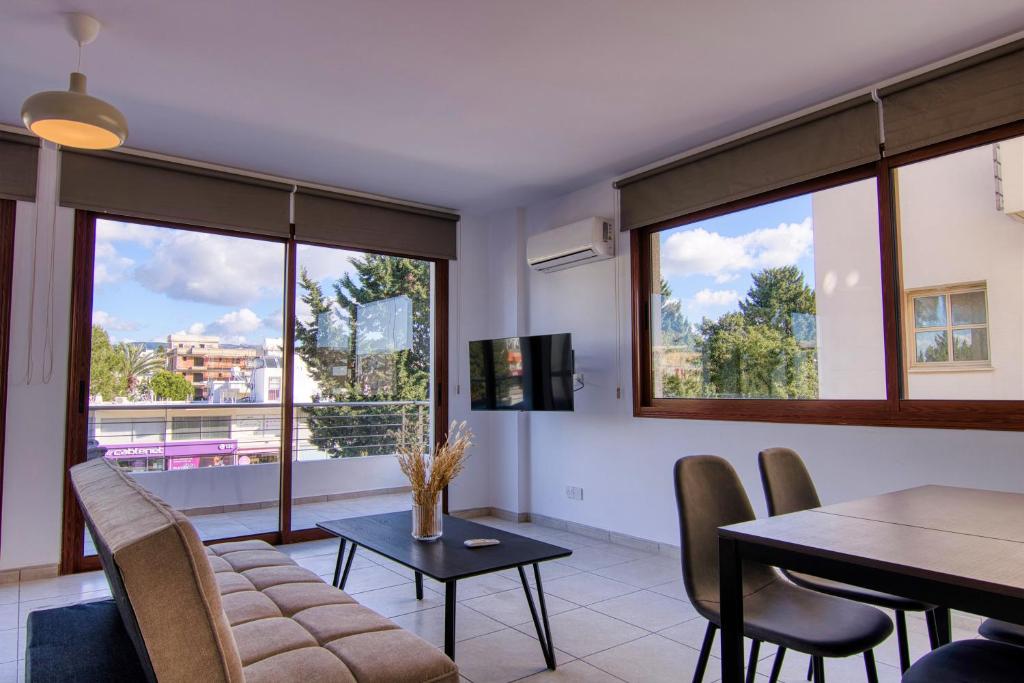 uma sala de estar com uma mesa, cadeiras e janelas em Phaedrus Living: City Flat Palas 103 em Pafos