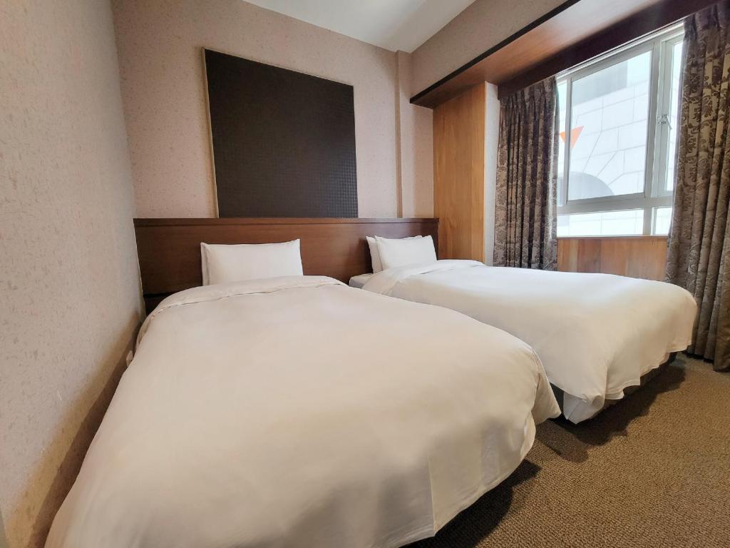 a hotel room with two beds and a window at CHECK inn Express Taichung Fengchia in Taichung