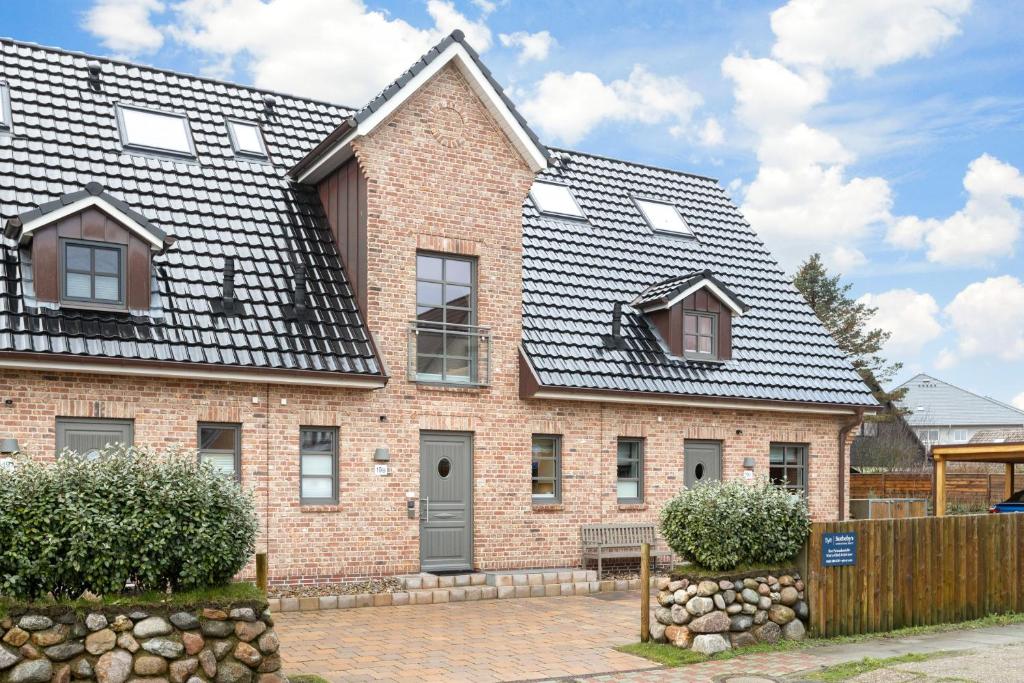 a brick house with a black roof at NEU! Ferienhaus Watt'n Glück Sylt in Westerland