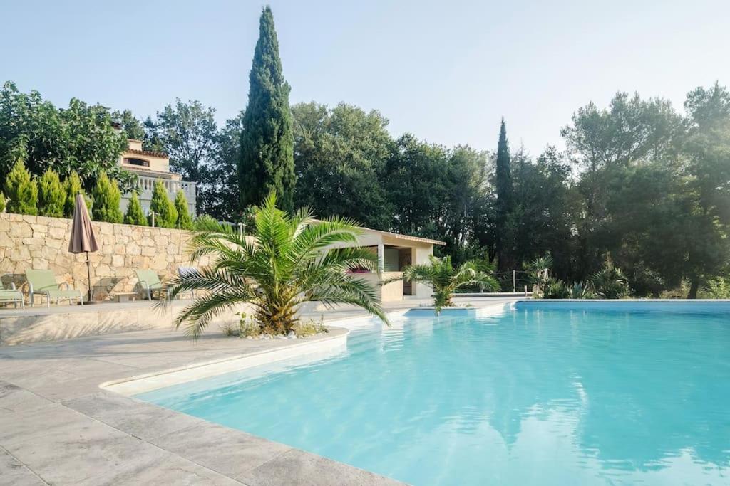 a large blue swimming pool with a house in the background at Villa Rhéa in Roquebrune-sur-Argens