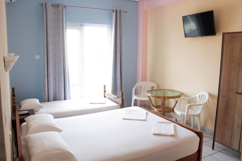 a bedroom with two beds and chairs and a window at Eleni Studio in Paralia Katerinis