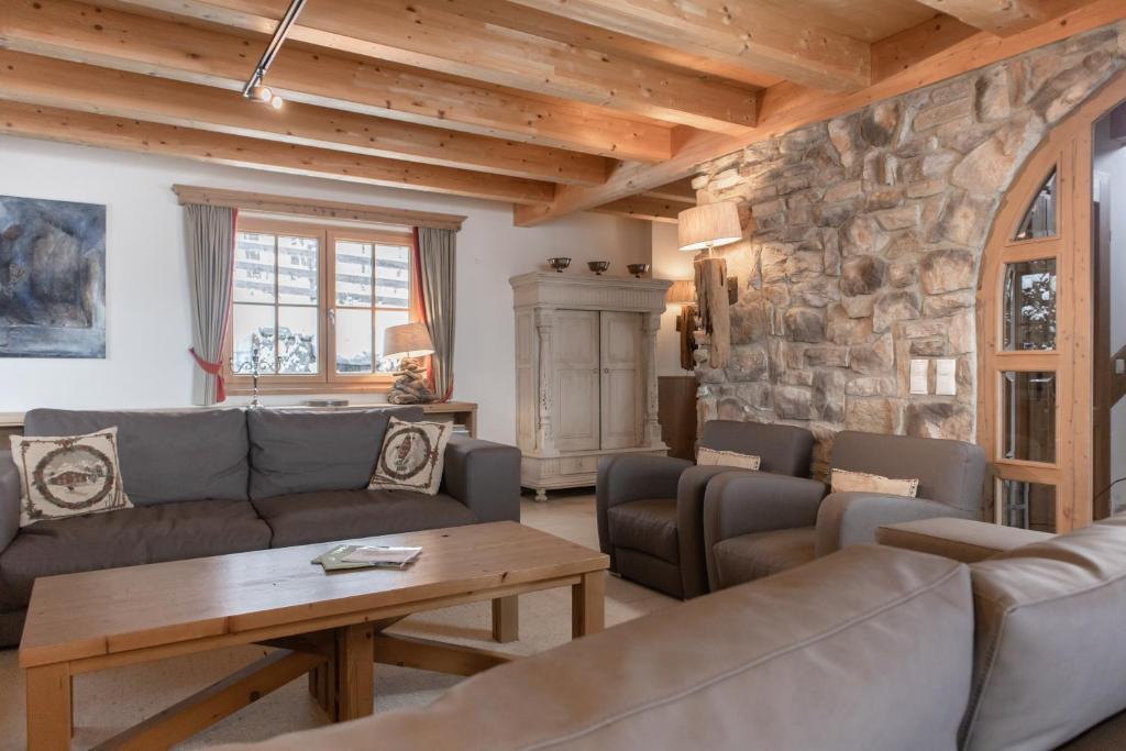 a living room with couches and a stone wall at AvenidA Panorama Chalet by Alpin Rentals in Piesendorf