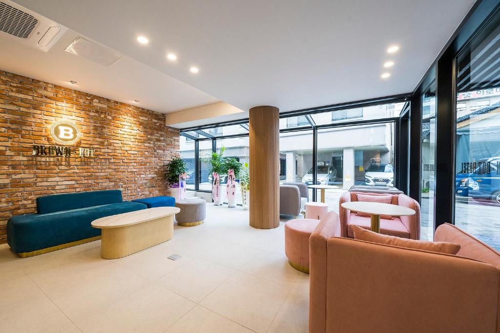 a lobby with blue and pink furniture and a brick wall at Browndot Hotel Namchuncheon in Chuncheon