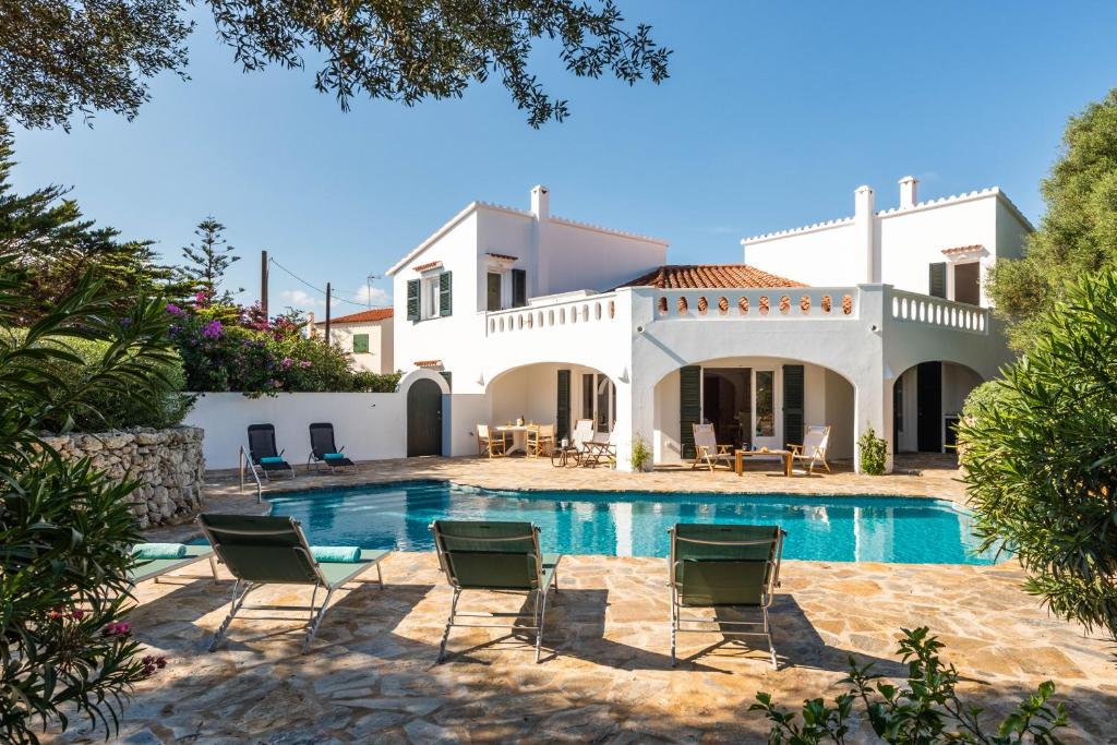 a villa with a swimming pool in front of a house at Casa Esquinera - Villa en Trebaluger in Es Castell