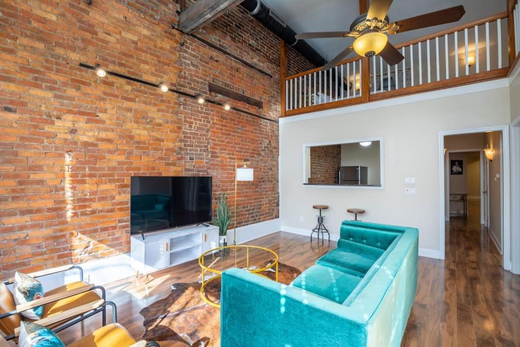 a living room with a blue couch and a brick wall at Ultra Chic Loft sleeps 4 in Fayetteville