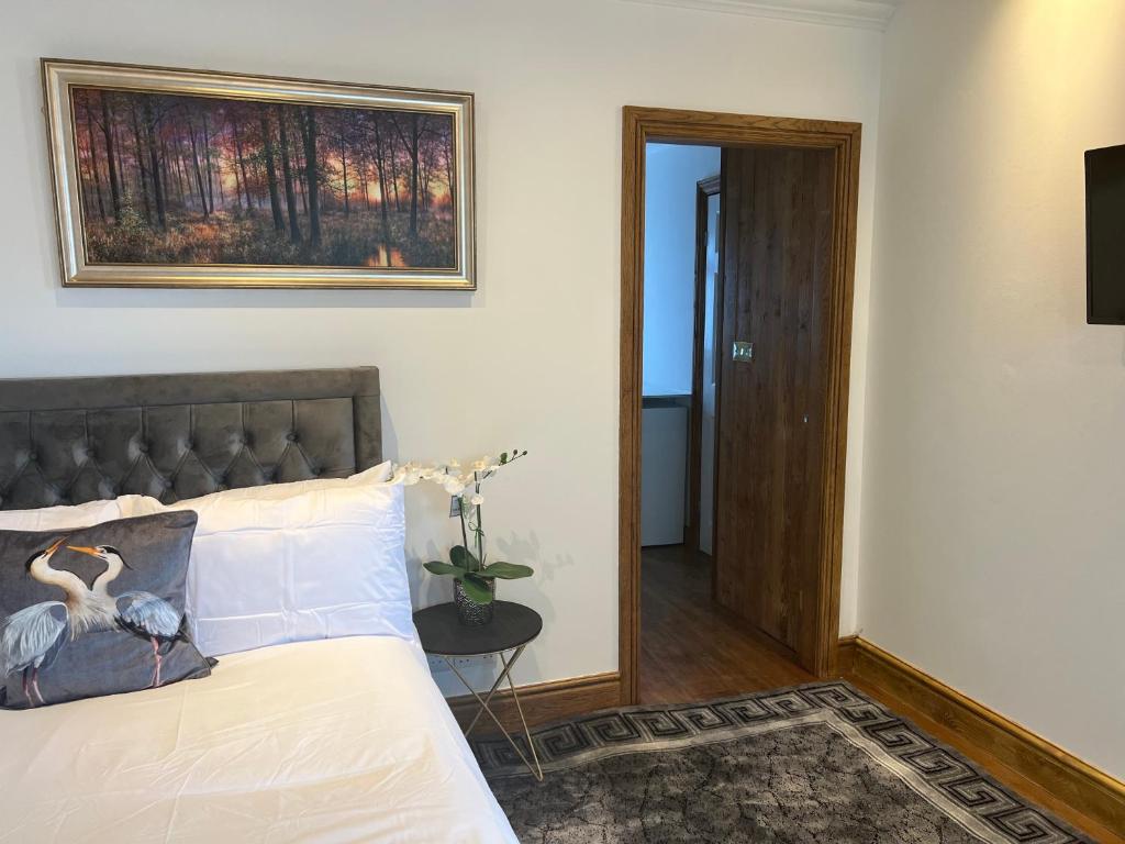 ein Schlafzimmer mit einem Bett mit einem Bild an der Wand in der Unterkunft TJ Homes - Luxury Studio Suite with Garden View - Next to tube station London in Ruislip