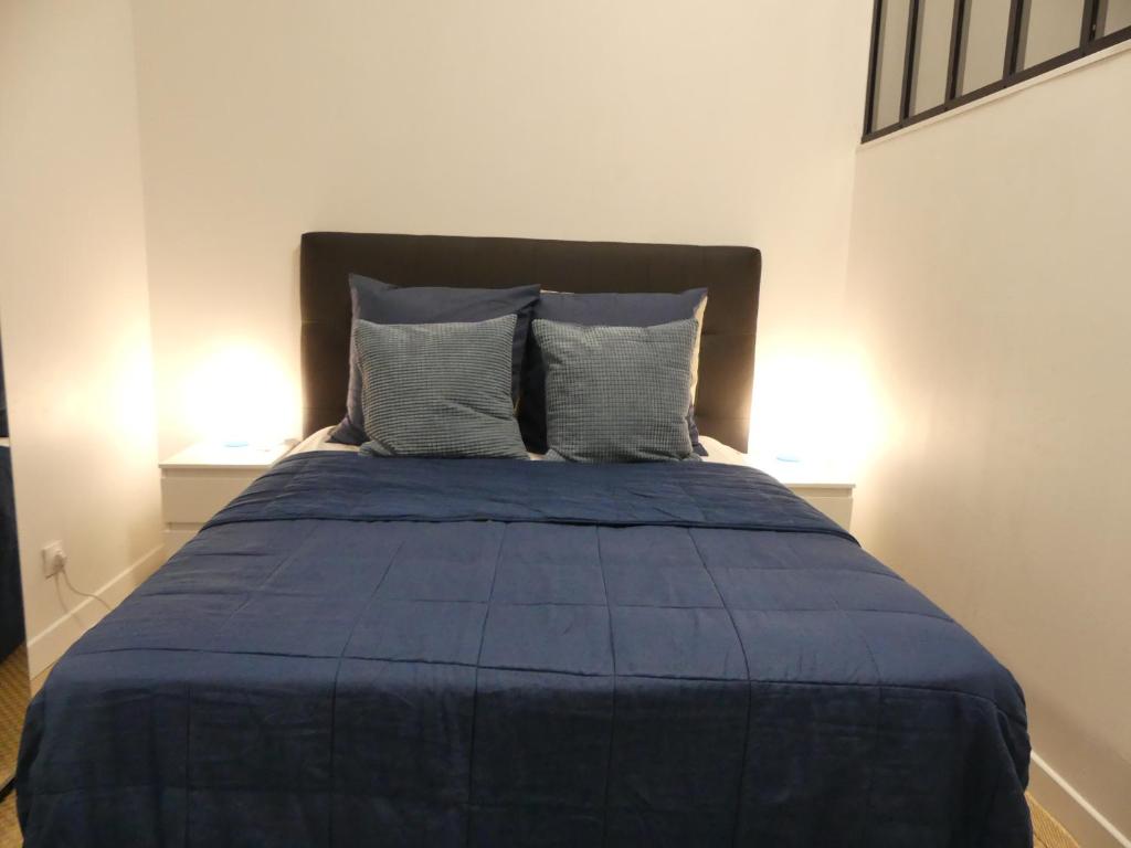 - un lit avec des draps et des oreillers bleus dans l'établissement Appartement Thida, à Paris