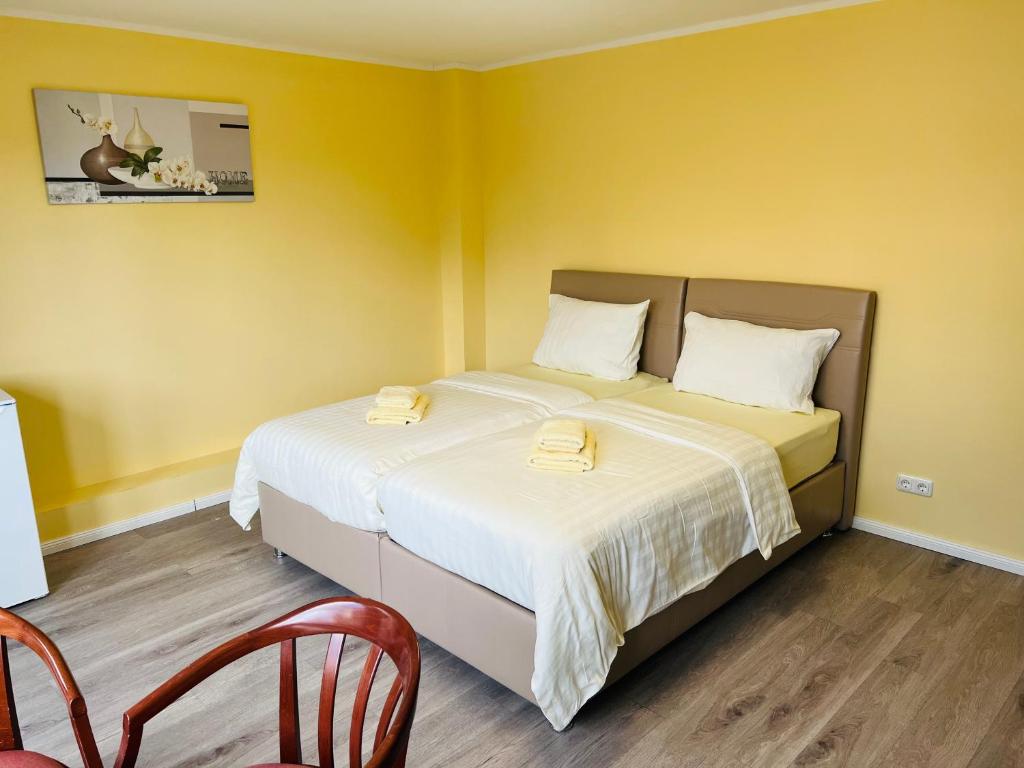 ノイ・ヴルムシュトルフにあるM&M Hotel - Neu Wulmstorfのベッドルーム1室(黄色の壁のベッド2台付)