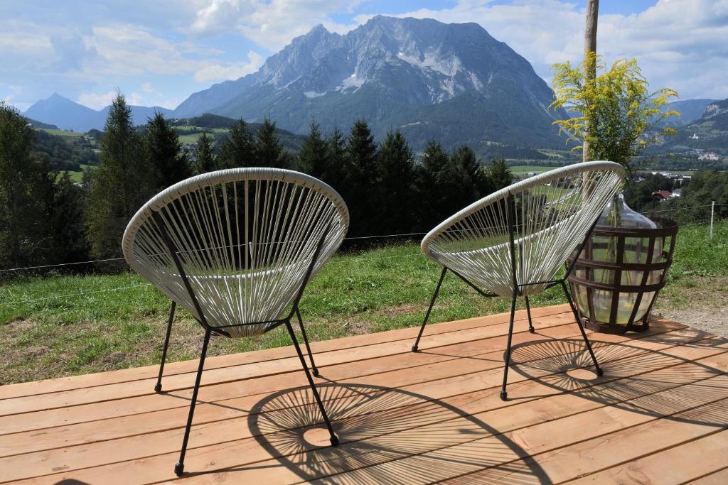 dos sillas sentadas en una terraza con una montaña en Glampingbus Lindwurm, en Irdning