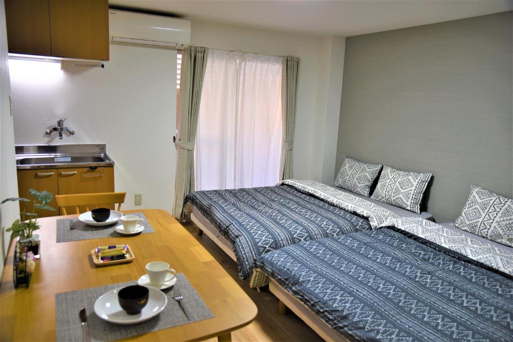 Momoyama-chōにあるU-shuku Kyoto Fushimiのベッド2台とテーブルが備わる小さな客室です。