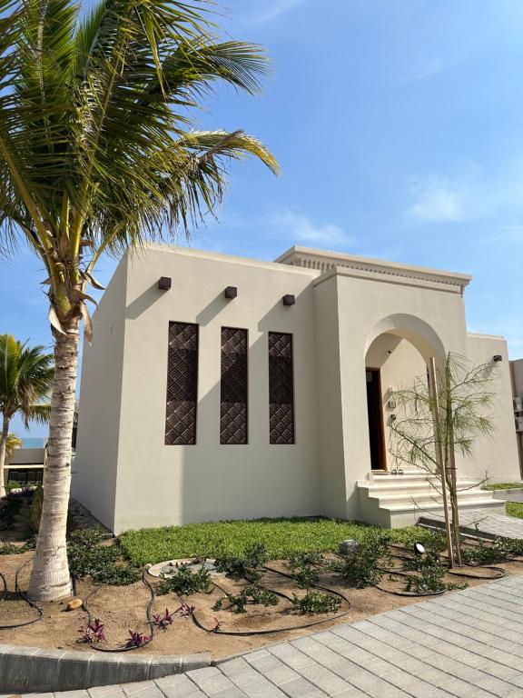a white church with palm trees in front of it at The Beach House in Muscat