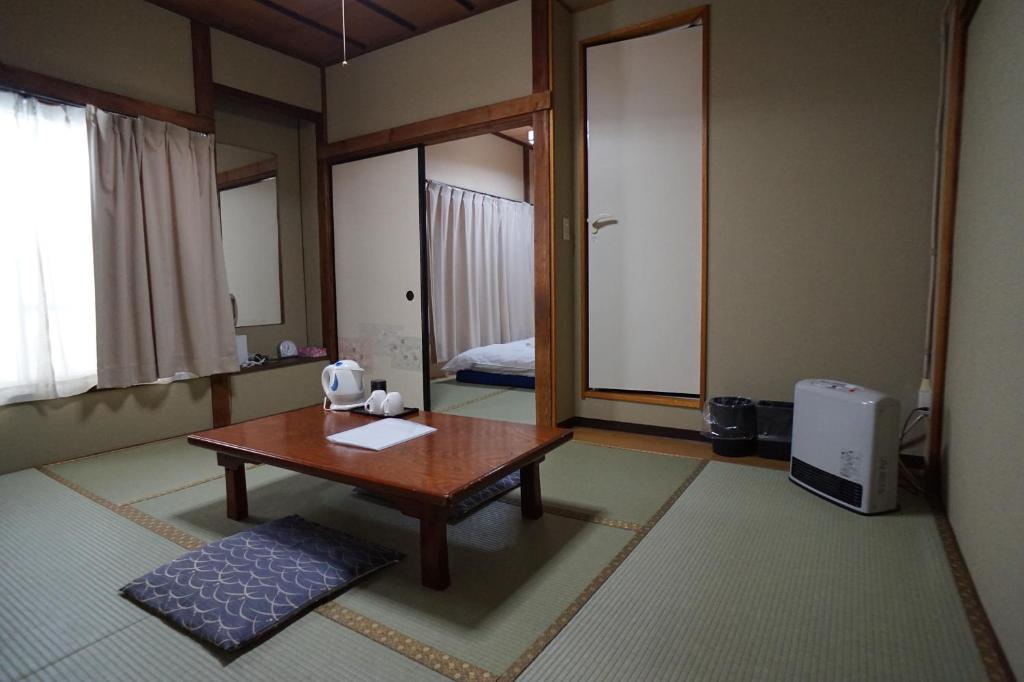 sala de estar con mesa y cama en Ryokan Katsutaro en Tokio