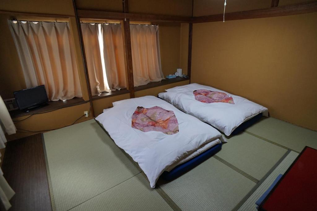 two beds in a small room with towels on them at Ryokan Katsutaro in Tokyo