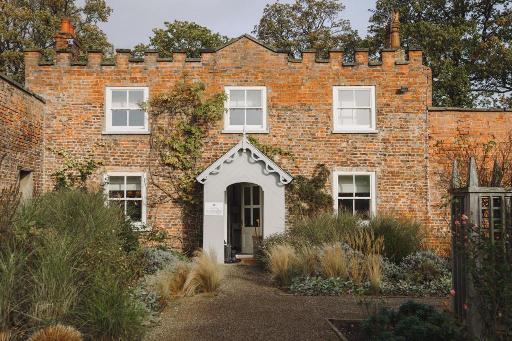 an old brick house with a white door at Gardeners Cottage, Wynyard Hall 