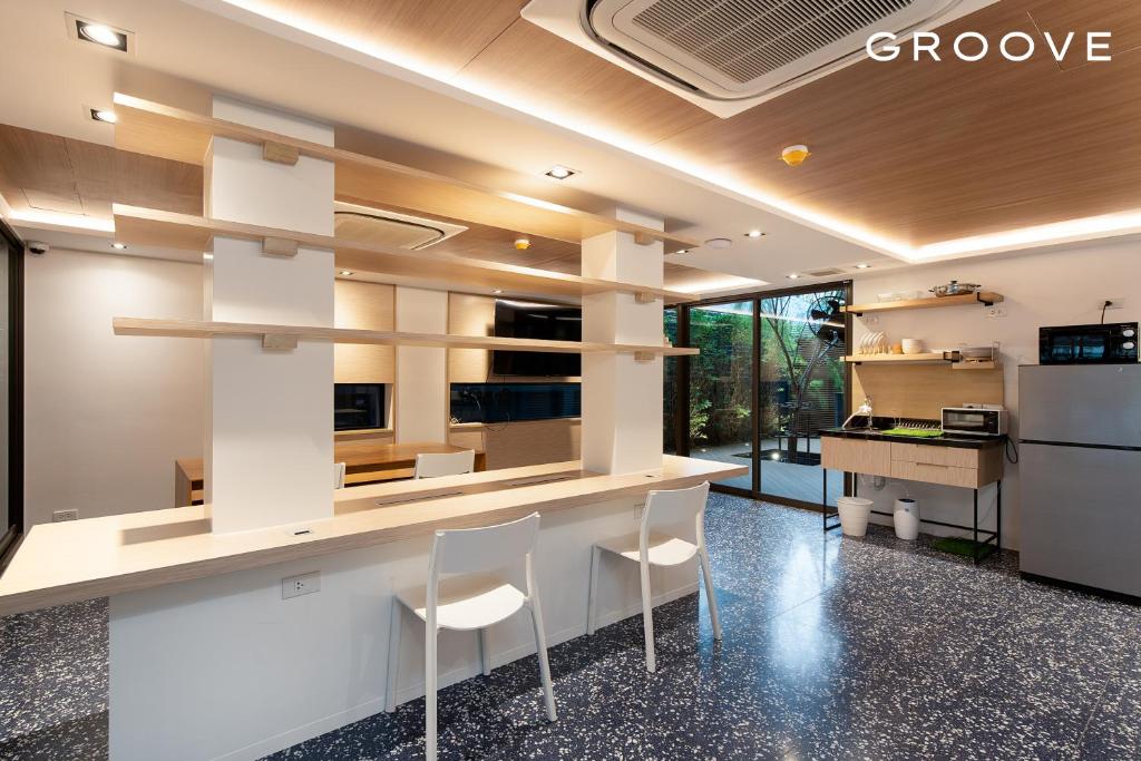 a kitchen with a counter and stools in a room at GROOVE AT SIAM in Pom Prap
