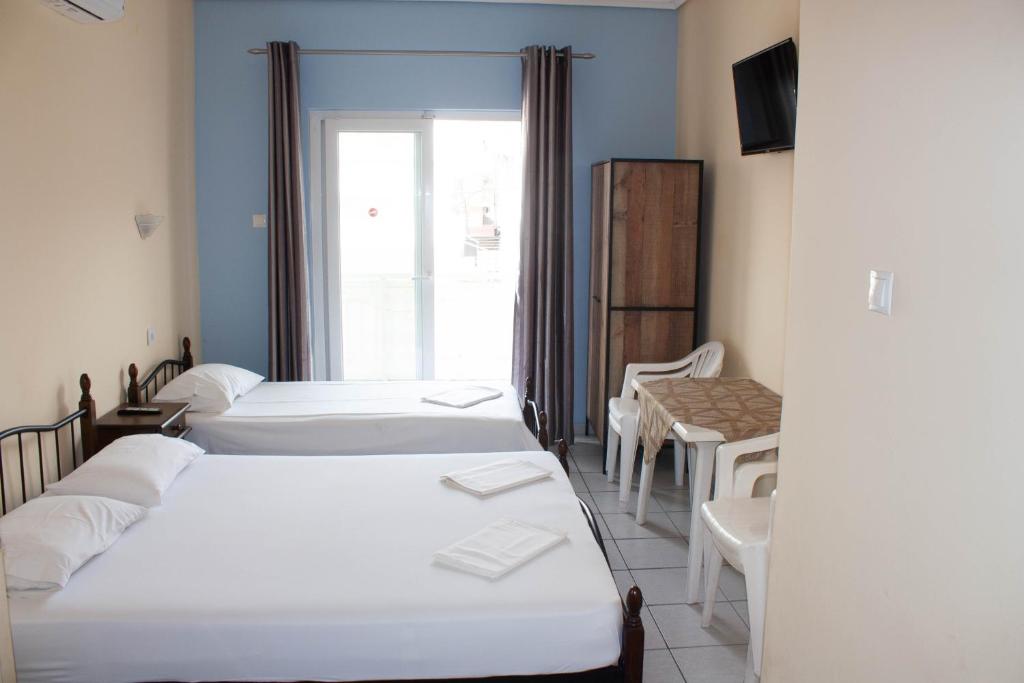 a room with three beds and a table and chairs at Hermes Studio in Paralia Katerinis