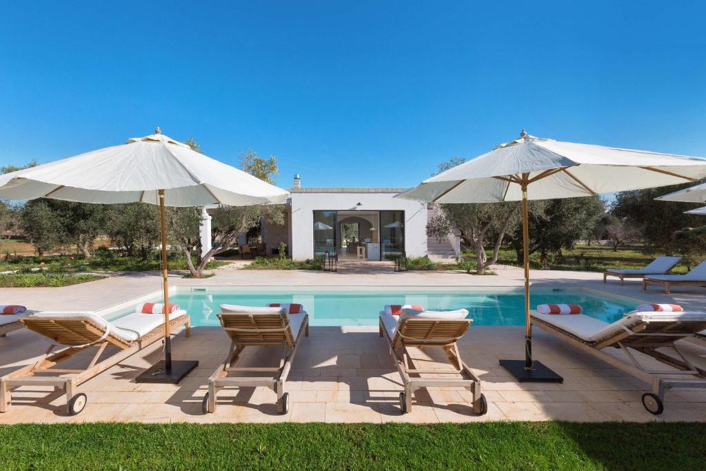 - un groupe de chaises longues et de parasols à côté de la piscine dans l'établissement Casa Diora by Perle di Puglia, à Carovigno