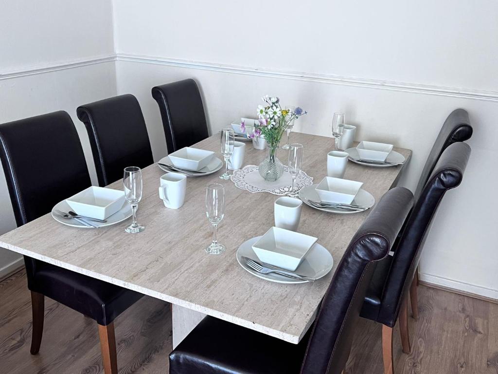 a dining room table with chairs and a table set with glasses at Beautiful 3-Bed House in High Wycombe in High Wycombe