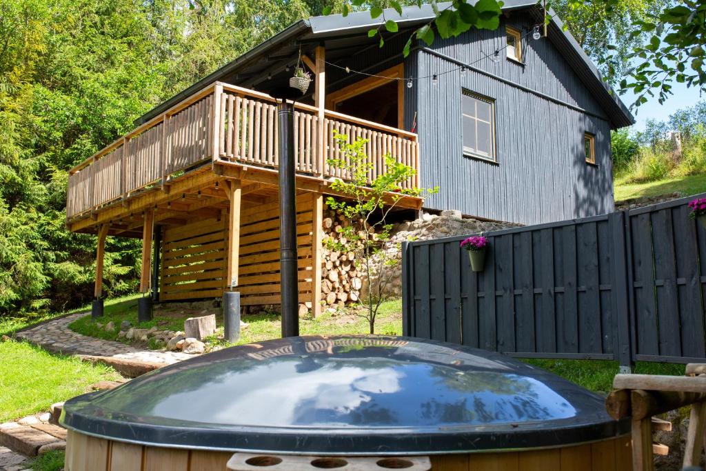 une cabane en rondins avec un bain à remous en face d'une maison dans l'établissement ACTIVFARM DOMKI NA KASZUBACH Domek Piotruś, à Gliśno