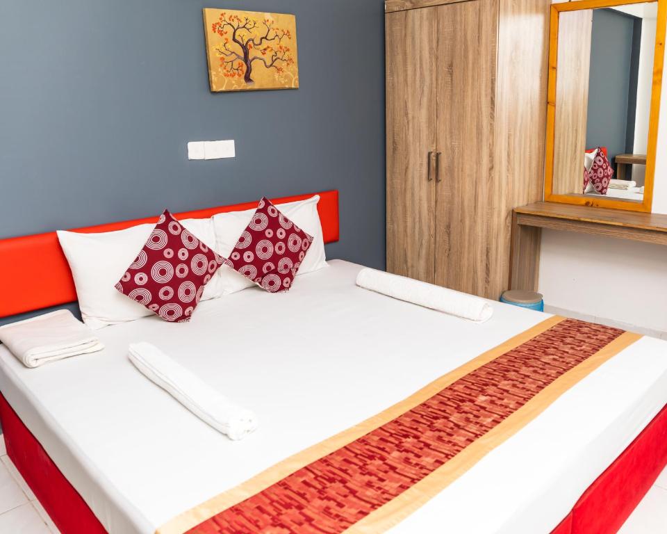 um quarto com uma cama com almofadas vermelhas e brancas em The G Ten Holiday Inn em Hulhumale