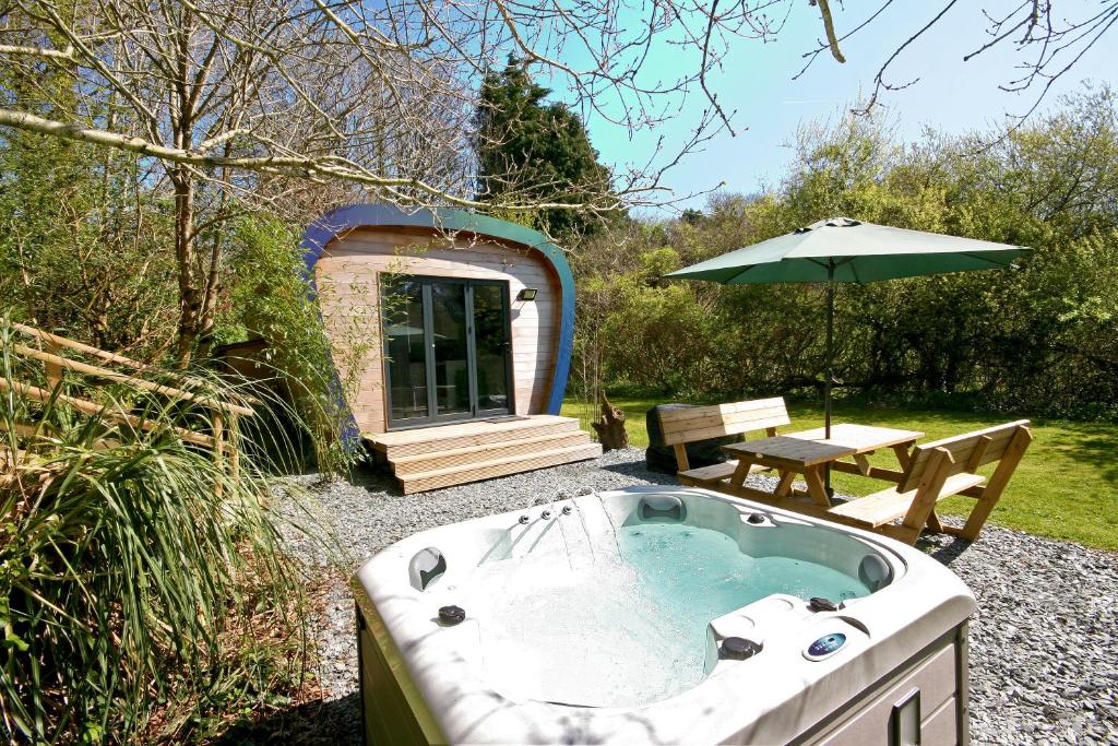 una bañera de hidromasaje en un patio con mesa y sombrilla en Sunridge EcoPod with Private Hot Tub, en Plymouth