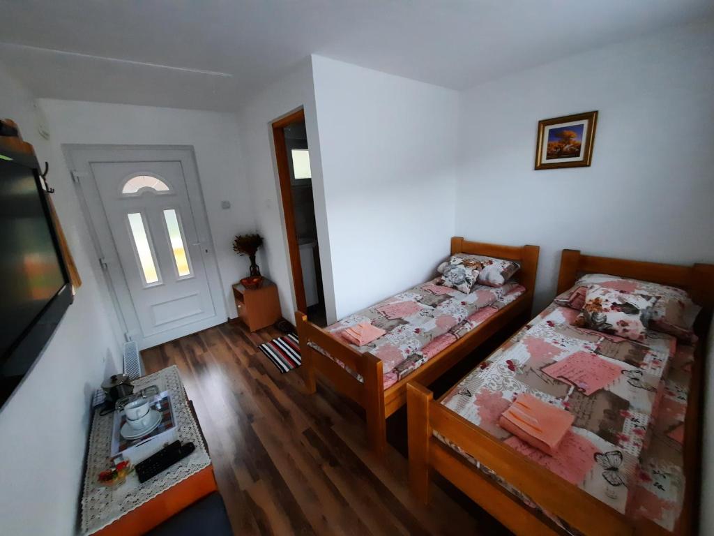 Habitación con 2 camas, TV y puerta en Apartmani Biser Drine en Foča