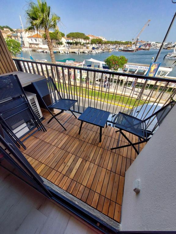 un pont avec deux tables et des chaises sur un bateau dans l'établissement Studio cabine vue port, au Grau-du-Roi