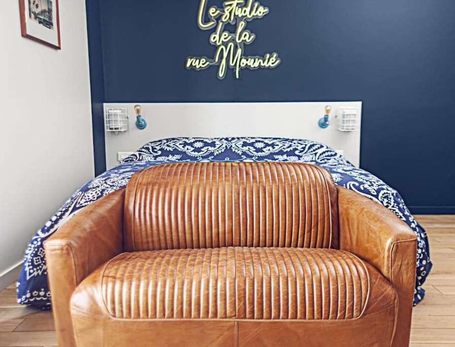 a brown leather couch in a room with a bed at Le Studio de la Rue Mounié in Antony